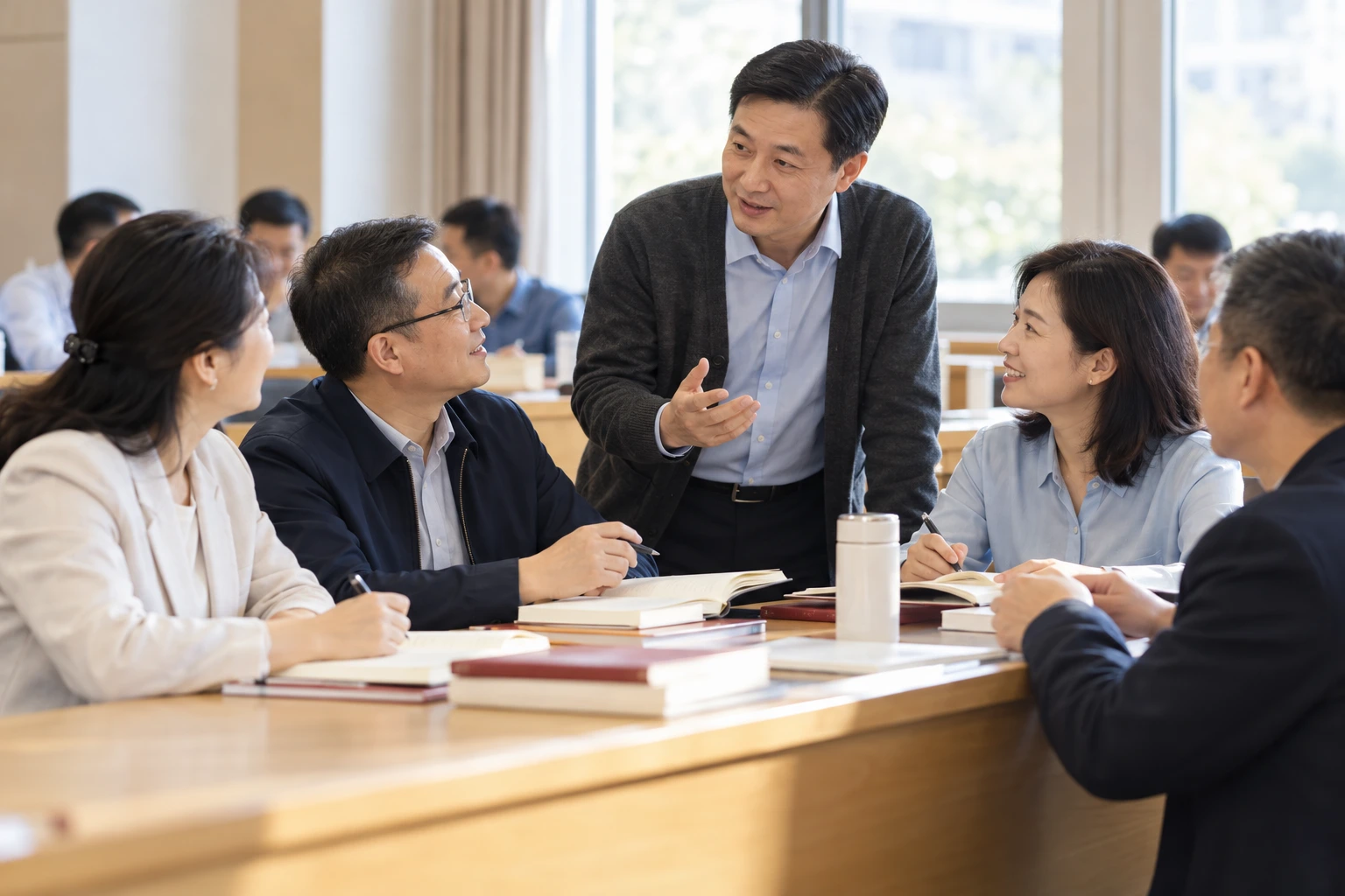 结业前班级教室内教师与成年学员交流学习收获,桌上课程资料,明亮自然,业务场景示意